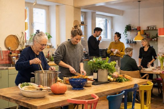 Gemeinsam kochen · Konzeptvisualisierung Unverbindliche KI-Konzeptvisualisierung einer warmen Gemeinschaftsküche, in der ältere und jüngere Nachbarn zusammen kochen.
